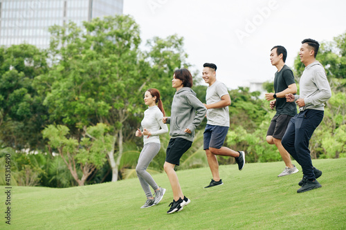 Group og young VIetnamese sportsmen running down the hill when training in city park