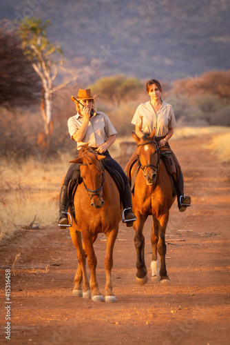 Two women on horseback one using radio © Nick Dale