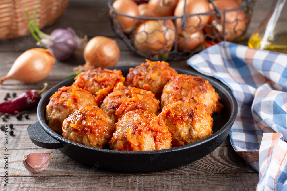 Meatballs from beef and pork with vegetables in a frying pan on a table Meatballs from beef and pork with vegetables in a frying pan on a table
