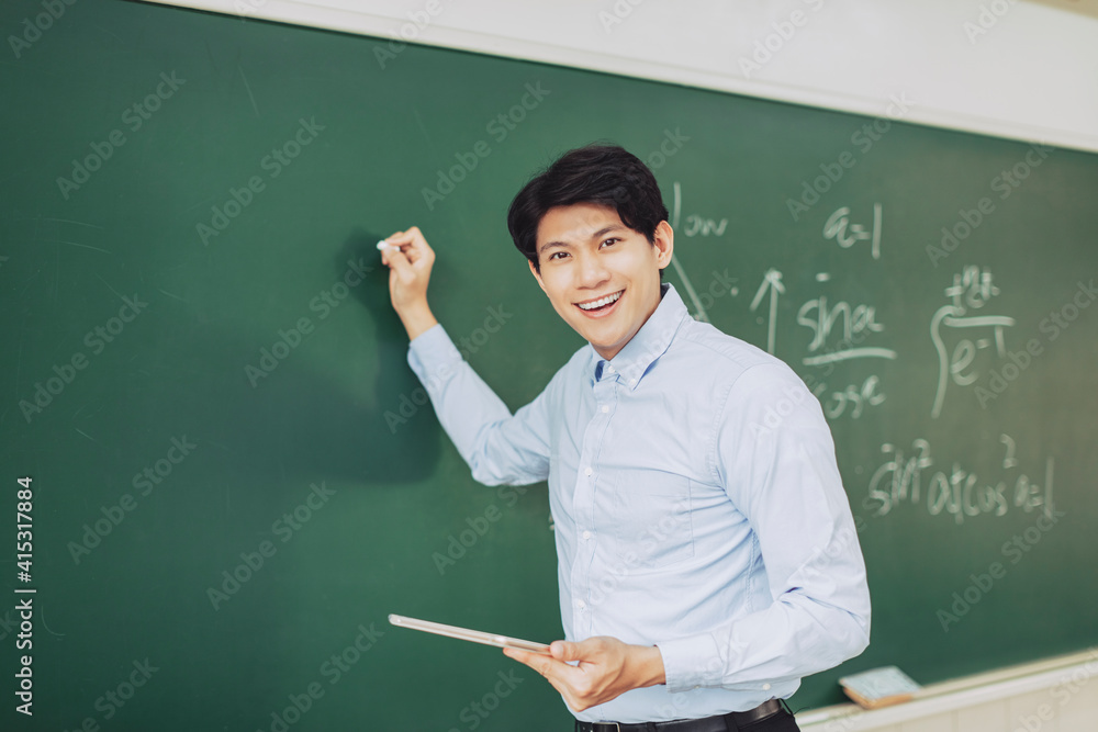 young smiling teacher standing in front of chalkboard young smiling teacher standing in front of chalkboard
