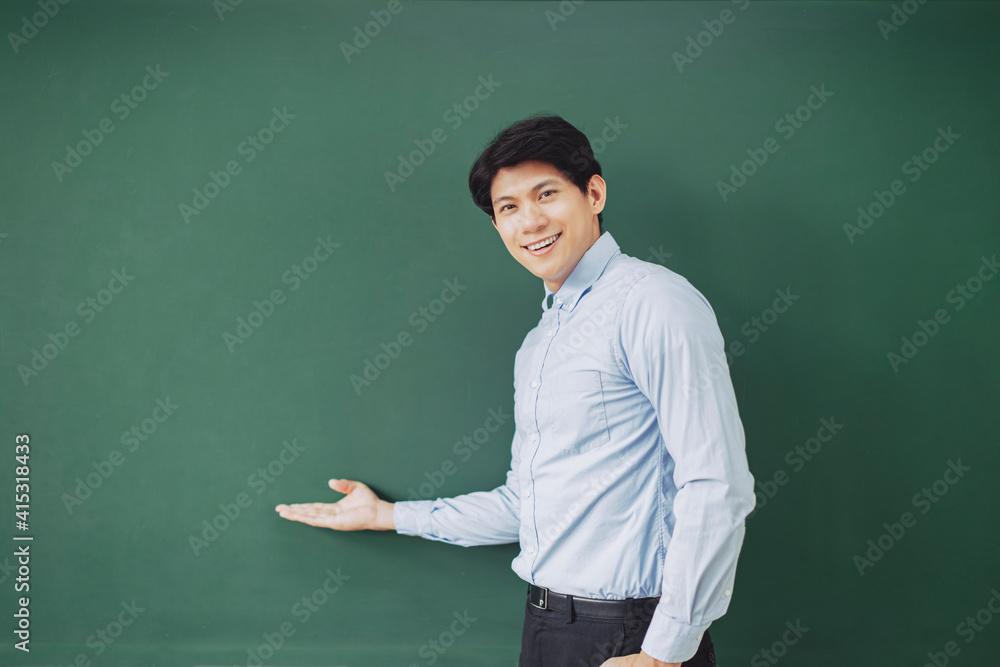 young smiling teacher standing in front of chalkboard young smiling teacher standing in front of chalkboard