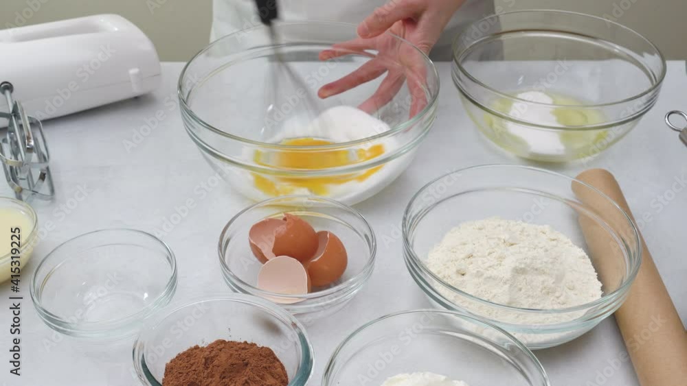 Cake batter recipe.Chef whisks egg yolks with sugar in a glass bowl, close up preparation process Cake batter recipe.Chef whisks egg yolks with sugar in a glass bowl, close up preparation process