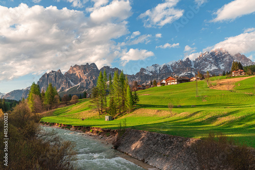Foto Beautiful alpine landscape of Italian dolomiti with river and green meadow