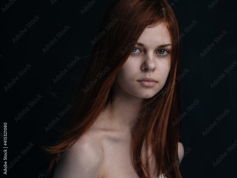 Portrait of a woman with red hair on a black background naked shoulders model Portrait of a woman with red hair on a black background naked shoulders model