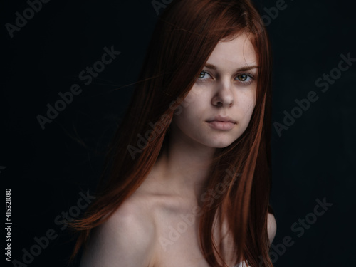 Portrait of a woman with red hair on a black background naked shoulders model