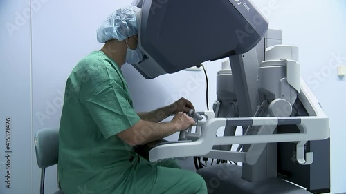 Surgeon operates with a medical robot looking inside the monitor.