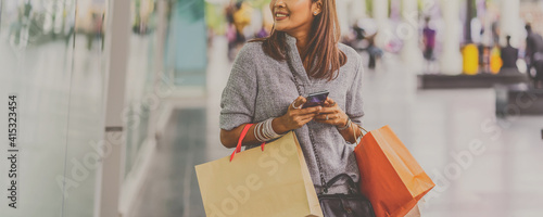 Banner cover of Asian woman using the smart mobile phone for check online shopping order with clothes beside the glassess in store shop at department center,shopaholic and fashion concept