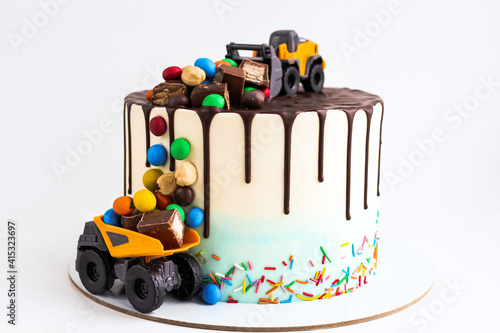 Birthday colorful cake for little boy with toy cars and colorful candies decorations. Holiday, celebration, stylish concept. Construction and transportation theme boys party.