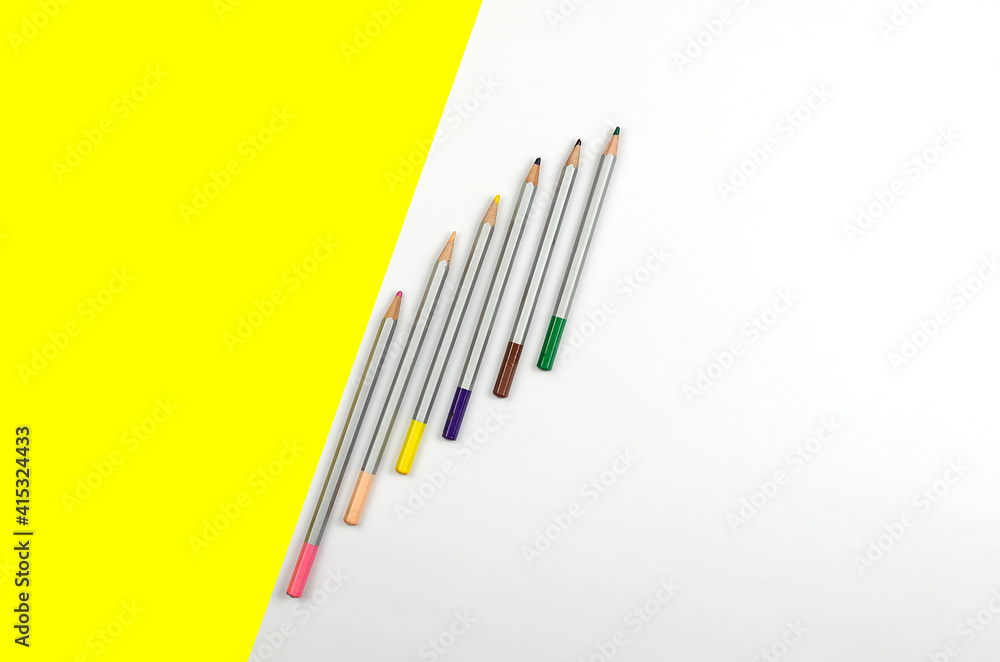 Flat lay composition with color pencils on white and yellow background. Flat lay composition with color pencils on white and yellow background.