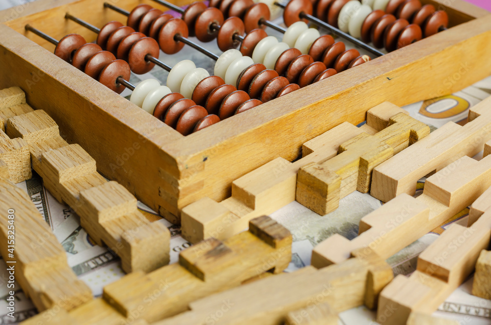 Wooden constructor details and old abacus cover American dollar bills. Wooden constructor details and old abacus cover American dollar bills.