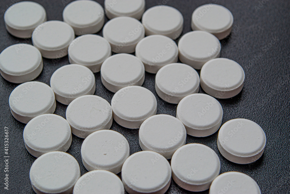 White round tablets on a black background. White round tablets on a black background.