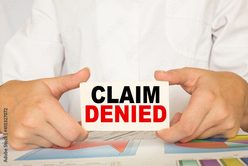 a man in the office holds a card with text CLAIM DENIED . business concept a man in the office holds a card with text CLAIM DENIED . business concept