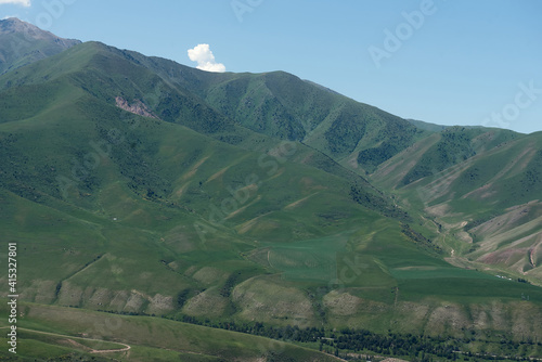 The nature of Kyrgyzstan. Summer. Mountain landscape. Among green valleys, mountains are visible at middle of the day. © dneezz
