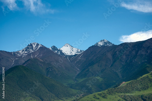 Mountain landscape of Kyrgyzstan. Among green valleys, mountains are visible at middle of the day. Tien Shan Mountains, Kyrgyzstan.