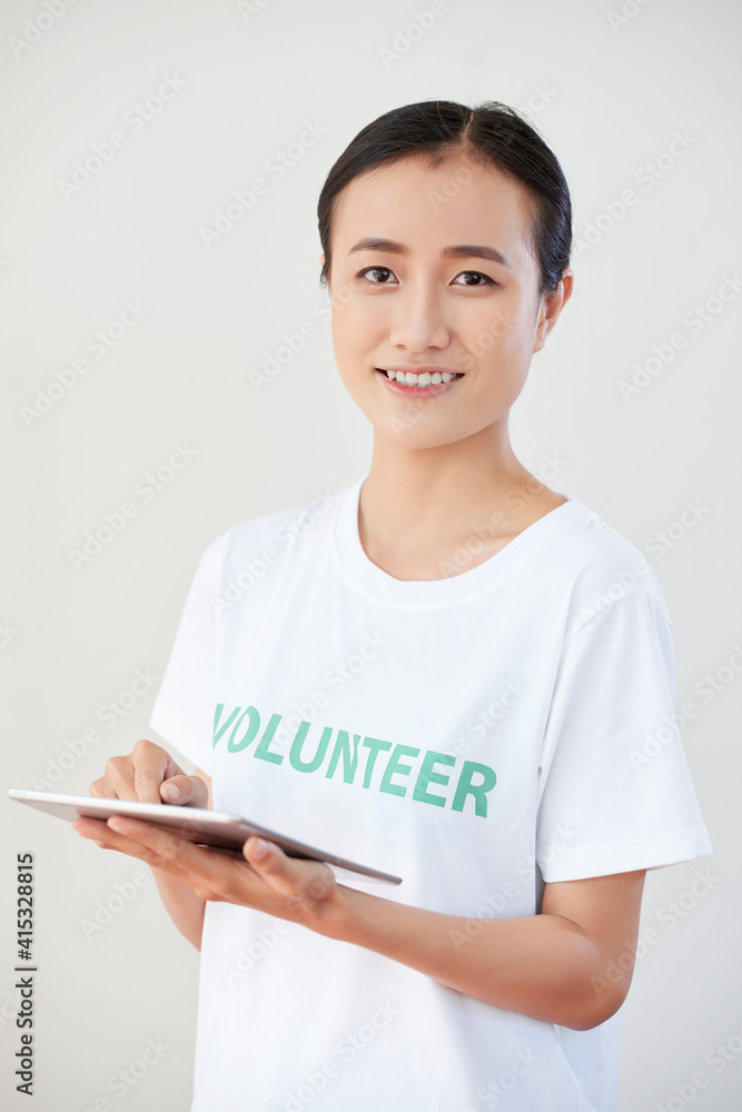 Happy smiling young volunteer organization member filling document or questionnaire on tablet computer Happy smiling young volunteer organization member filling document or questionnaire on tablet computer