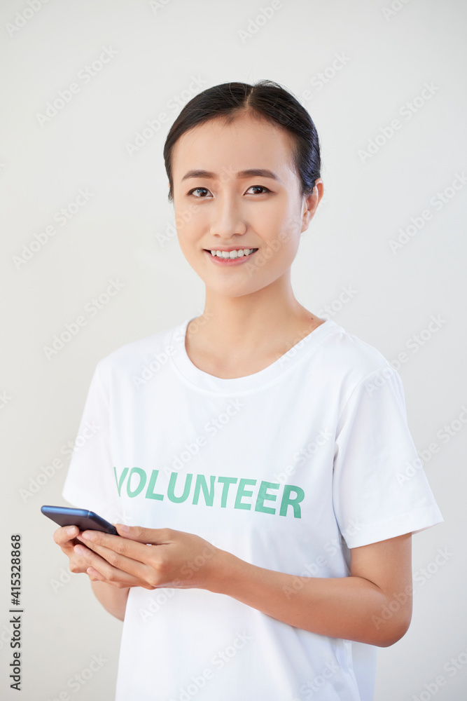 Pretty smiling young volunteer texting frineds and inviting them to take part in upcoming event Pretty smiling young volunteer texting frineds and inviting them to take part in upcoming event