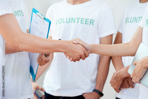 Head of volunteers with clipboard shaking hand of new organization member
