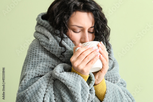 Sick young woman with hot tea on color background