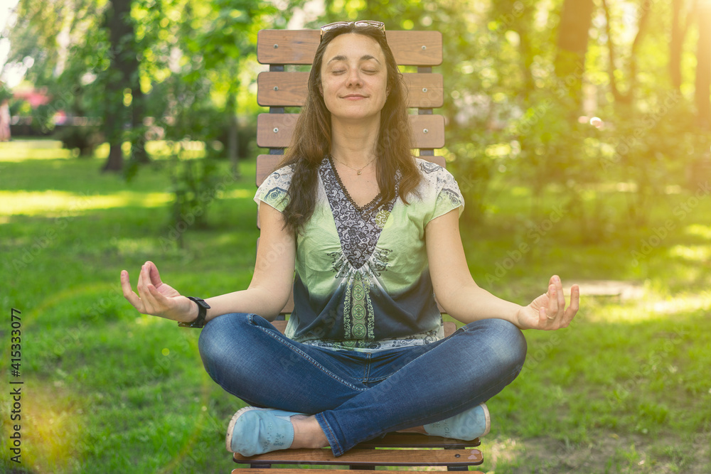 Young girl doing yoga and meditating in the city park on a sunny day. Sitting on a wooden bench. toned Young girl doing yoga and meditating in the city park on a sunny day. Sitting on a wooden bench. toned