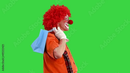 Funny clown on a walk with shopping bags on a Green Screen, Chroma Key.