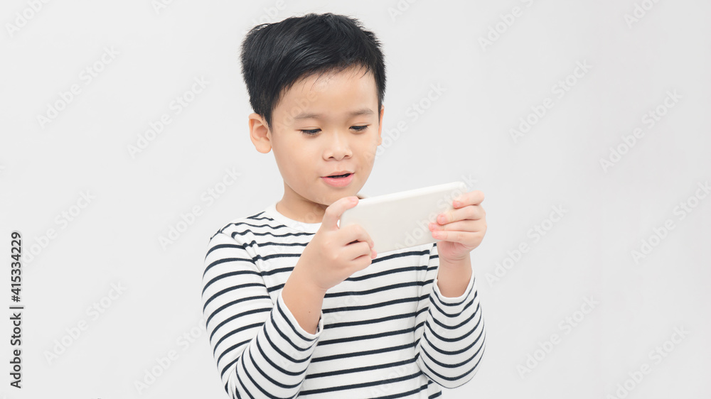 Asian child focused and concentrated playing with mobile phone in kid suffering gaming addiction concept Asian child focused and concentrated playing with mobile phone in kid suffering gaming addiction concept