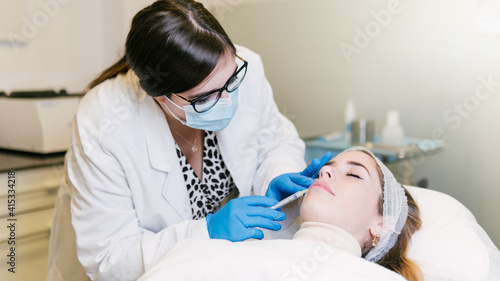 A Woman getting an injection on her lips and face by a doctor. Beauty anti aging treatment at a clinic