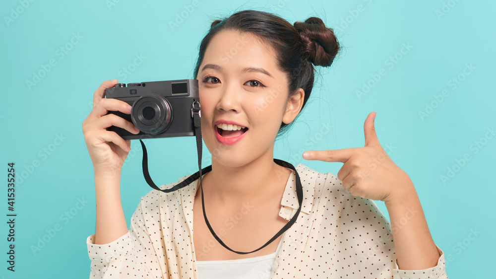 Pretty cool young woman model with retro film camera over blue background