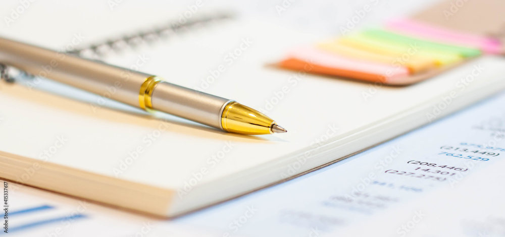 Fototapeta premium Close up of golden pen on notepad background