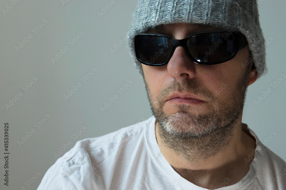 Portrait of a man in sunglasses, a winter hat and a white T-shirt Portrait of a man in sunglasses, a winter hat and a white T-shirt
