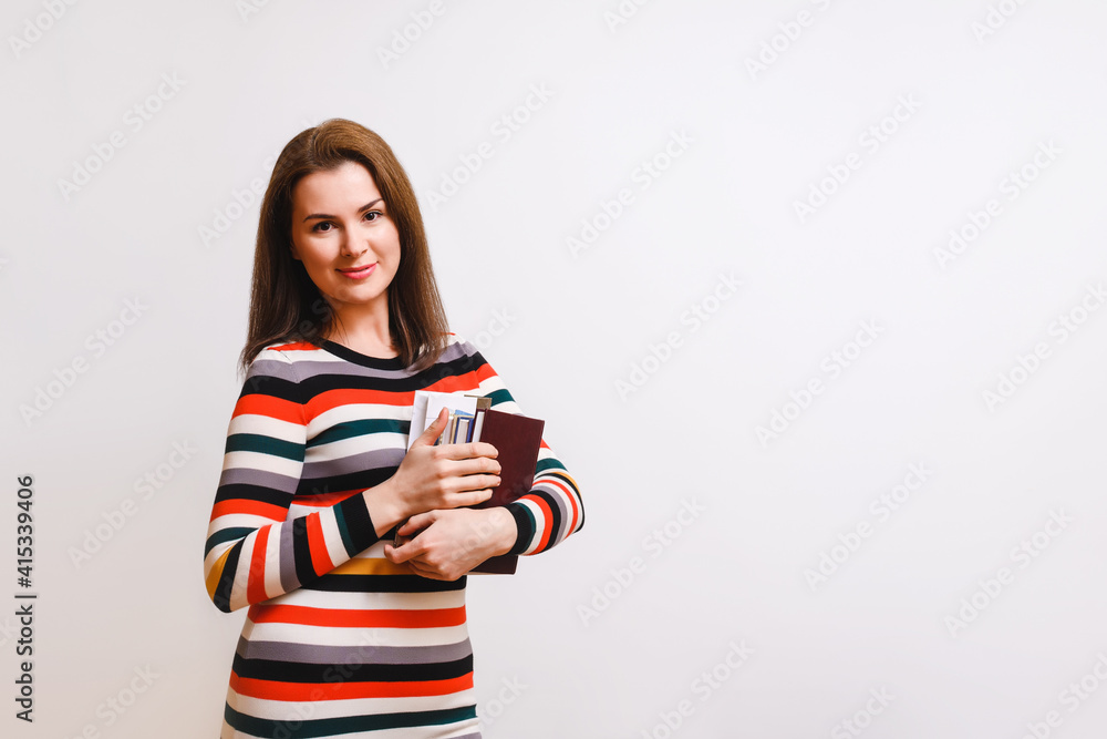 beautiful brown-haired woman in a multi-colored dress holds books in her hands and looks into the camera. Education concept. Studio shot on white background, copy space beautiful brown-haired woman in a multi-colored dress holds books in her hands and looks into the camera. Education concept. Studio shot on white background, copy space