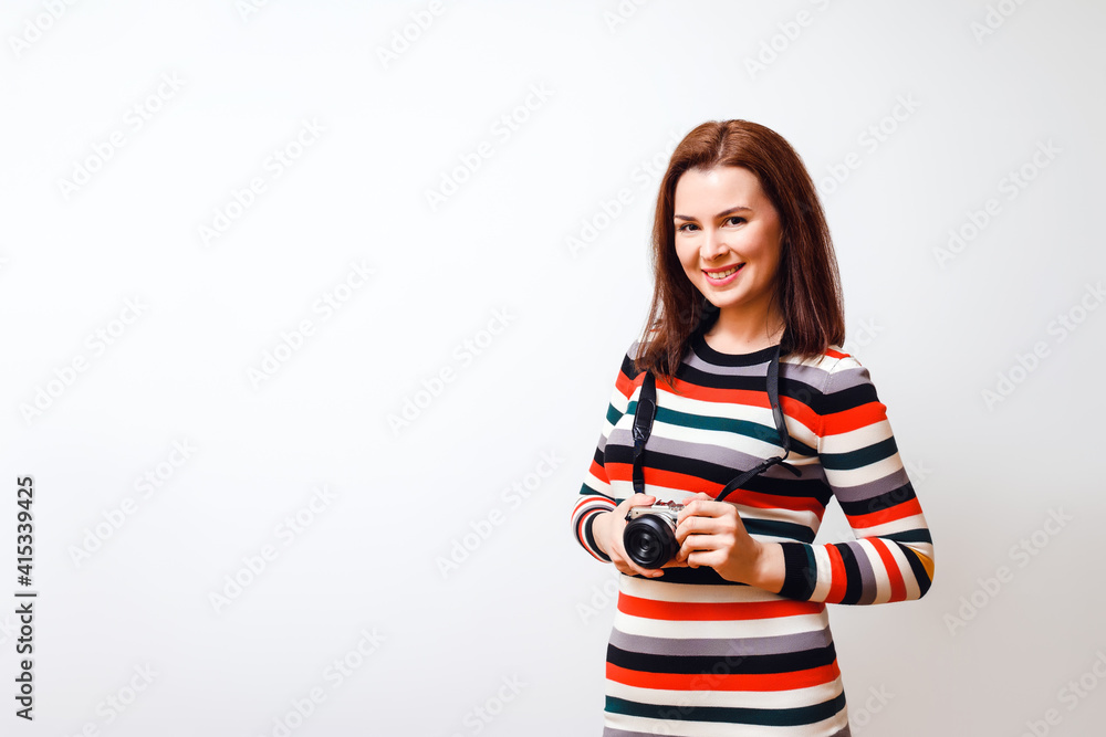 attractive woman in multi-colored dress holds a camera and smiles. Horizontal studio shot on a white background. Copy space attractive woman in multi-colored dress holds a camera and smiles. Horizontal studio shot on a white background. Copy space