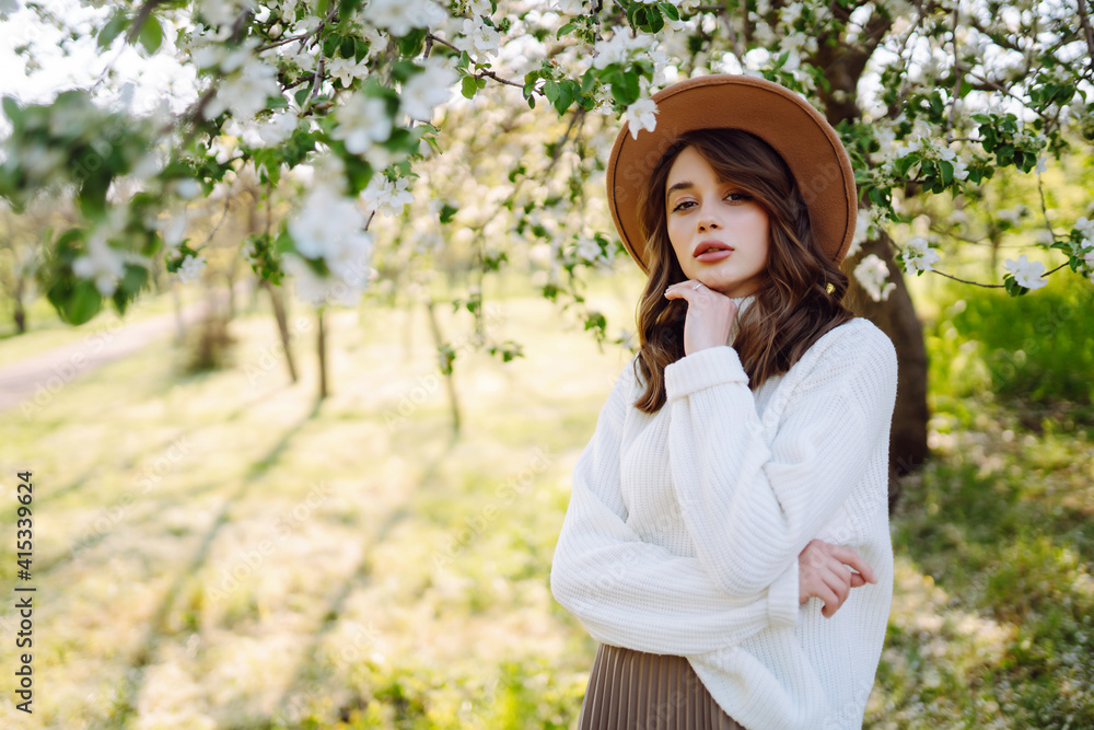 Young woman posing in spring blossom flowers in blooming garden. Female beauty, fashion. City lifestyle. 
