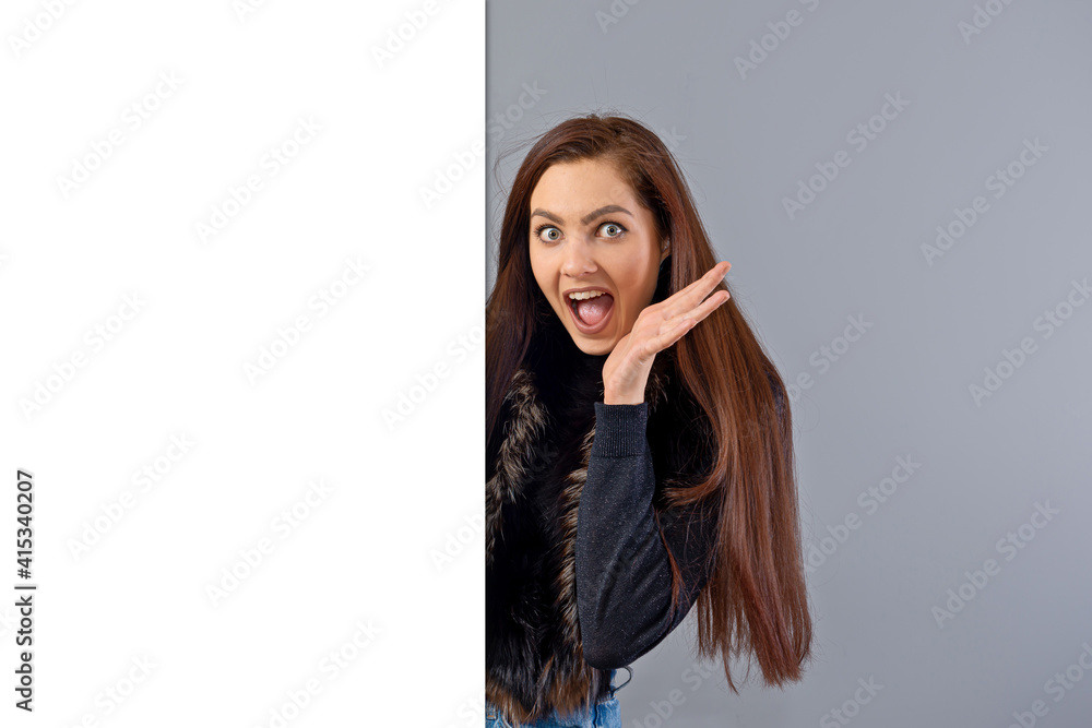 emotional young teenager woman showing blank signboard with copy space, isolated on gray