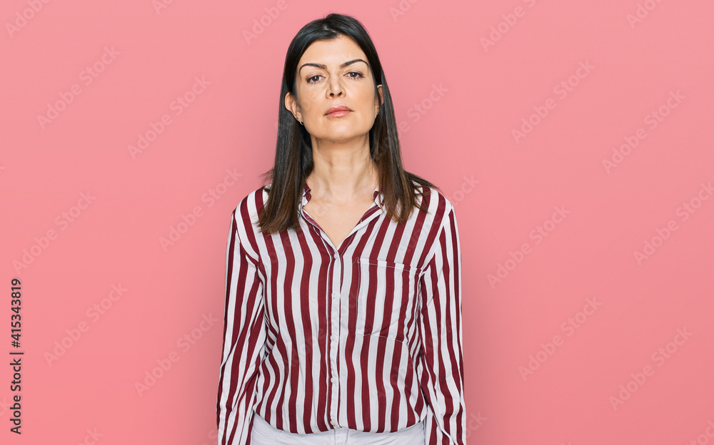 Fototapeta premium Beautiful brunette woman wearing striped shirt relaxed with serious expression on face. simple and natural looking at the camera.