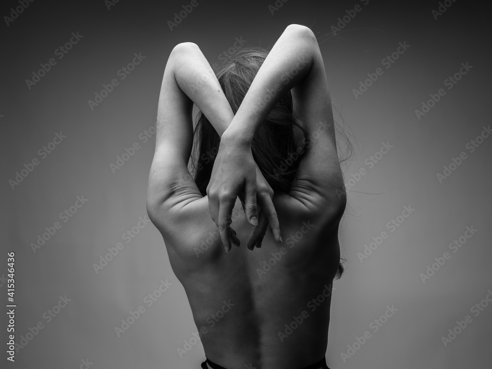 Nude woman in black and white photo gesturing with hands back view