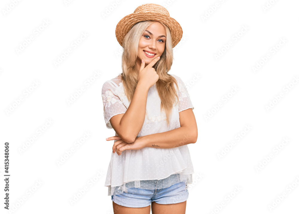 Young blonde girl wearing summer hat looking confident at the camera smiling with crossed arms and hand raised on chin. thinking positive. Young blonde girl wearing summer hat looking confident at the camera smiling with crossed arms and hand raised on chin. thinking positive.