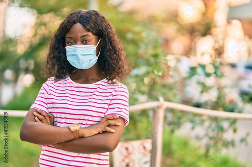 Young african american girl wearing medical mask standing at the park.