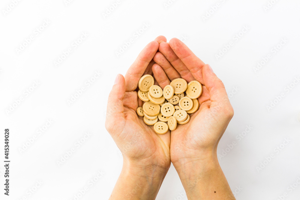 two hands holding a handful of wooden buttons on white background two hands holding a handful of wooden buttons on white background