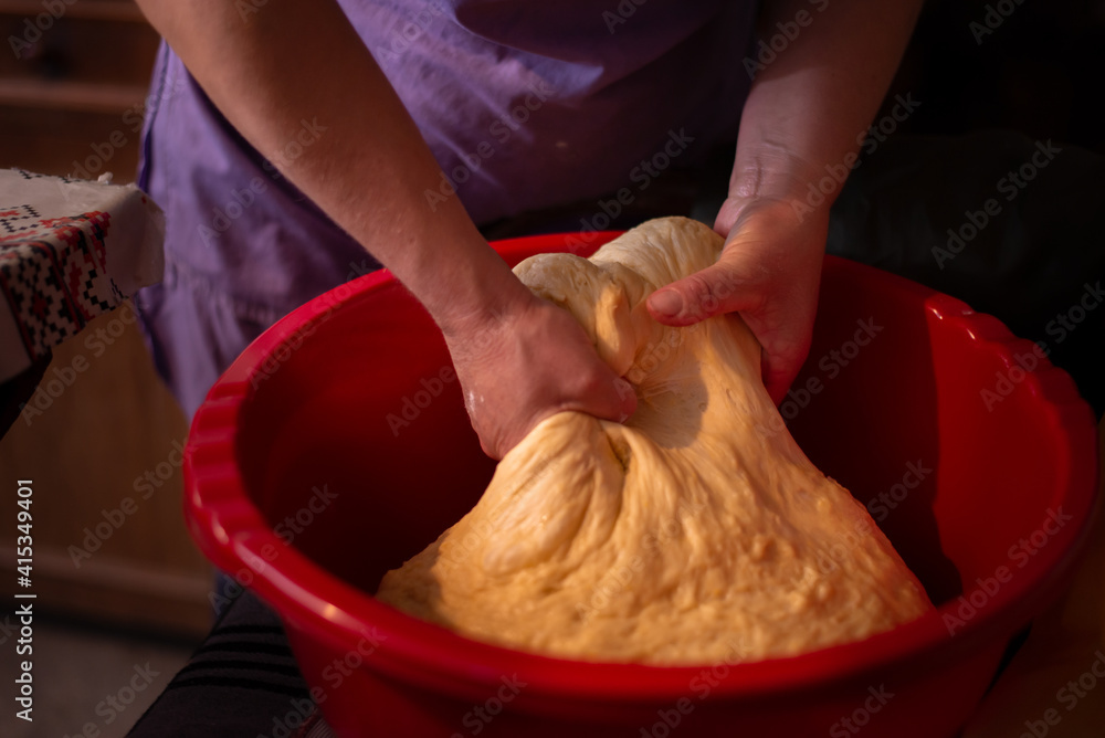 Fototapeta premium housewife kneading the dough by hand. preparation of the recipe for traditional Romanian homemade cakes known as cozonac