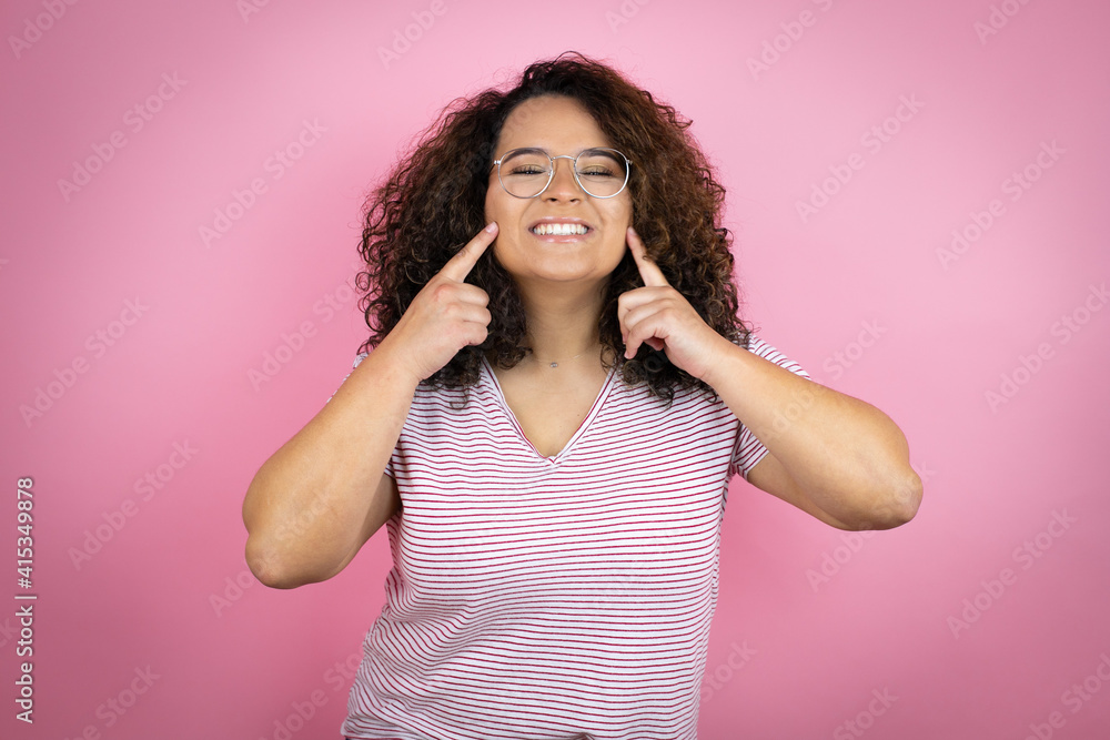 Young african american woman wearing red stripes t-shirt over pink background smiling confident showing and pointing with fingers teeth and mouth Young african american woman wearing red stripes t-shirt over pink background smiling confident showing and pointing with fingers teeth and mouth