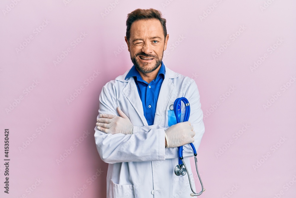 Middle age man wearing doctor uniform winking looking at the camera with sexy expression, cheerful and happy face. Middle age man wearing doctor uniform winking looking at the camera with sexy expression, cheerful and happy face.