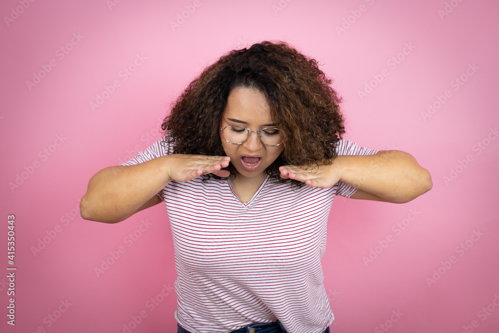 Young african american woman wearing red stripes t-shirt over pink background shouting and screaming loud down with hands on mouth