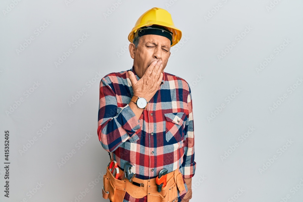 Senior hispanic man wearing handyman uniform bored yawning tired covering mouth with hand. restless and sleepiness.