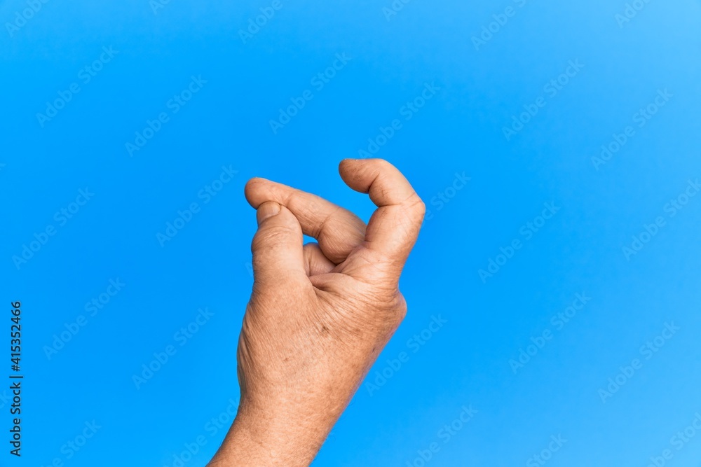 Hand of senior hispanic man over blue isolated background snapping fingers for success, easy and click symbol gesture with hand Hand of senior hispanic man over blue isolated background snapping fingers for success, easy and click symbol gesture with hand