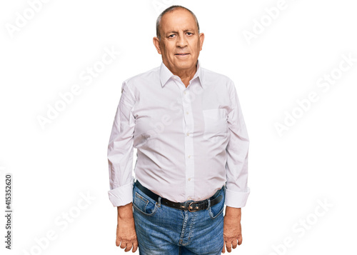 Handsome senior man wearing elegant white shirt relaxed with serious expression on face. simple and natural looking at the camera.