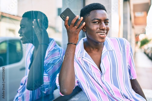 Young african american man smiling happy tallking on the smartphone at street of city. photo