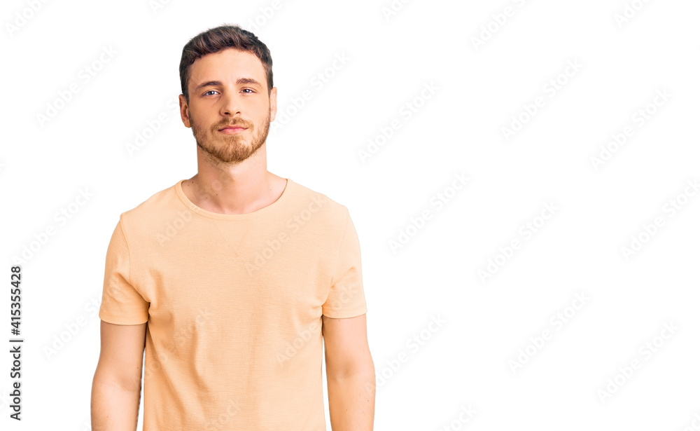 Fototapeta premium Handsome young man with bear wearing casual yellow tshirt relaxed with serious expression on face. simple and natural looking at the camera.
