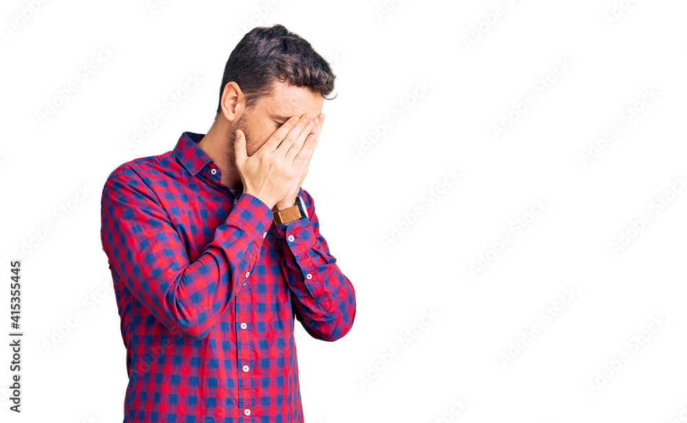 Handsome young man with bear wearing casual shirt with sad expression covering face with hands while crying. depression concept. Handsome young man with bear wearing casual shirt with sad expression covering face with hands while crying. depression concept.