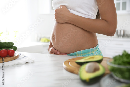 Young pregnant woman near table in kitchen  closeup. Taking care of baby health