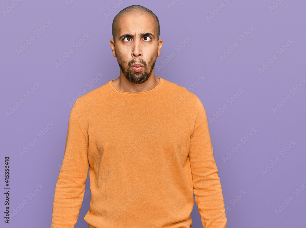 Fototapeta premium Hispanic adult man wearing casual winter sweater making fish face with lips, crazy and comical gesture. funny expression.